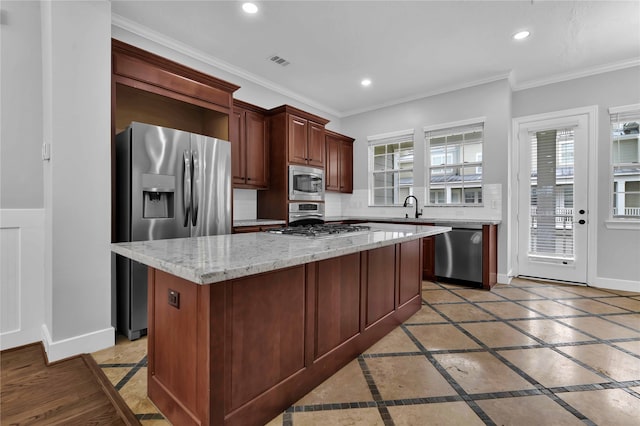 kitchen featuring stainless steel appliances, sink, ornamental molding, a center island, and decorative backsplash