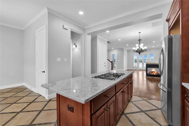 kitchen with stainless steel appliances, light stone counters, hanging light fixtures, ornamental molding, and a kitchen island