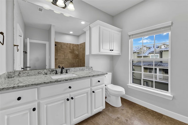 bathroom with toilet, vanity, and a tile shower