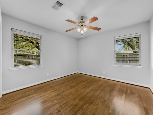 empty room featuring wood-type flooring, plenty of natural light, and ceiling fan