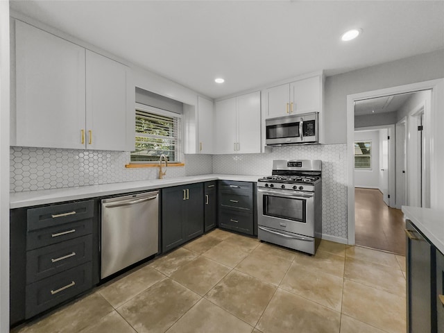 kitchen featuring white cabinets, sink, decorative backsplash, light tile patterned floors, and stainless steel appliances