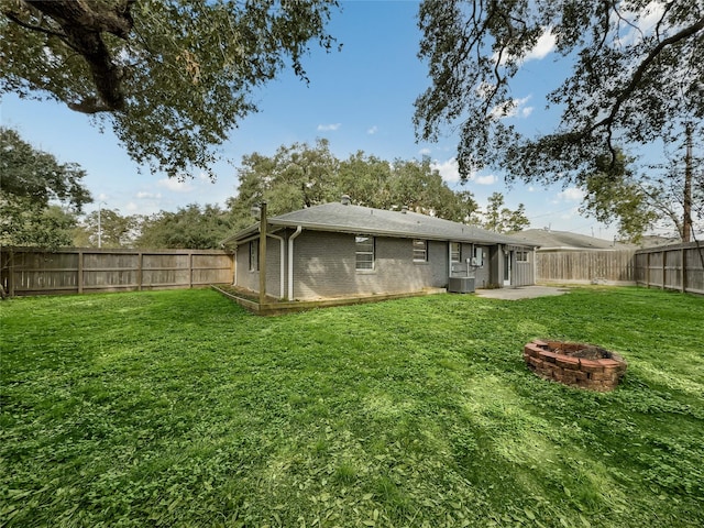 rear view of house with a yard, cooling unit, a patio, and an outdoor fire pit