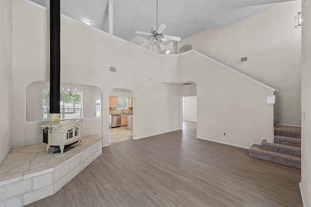 living room with high vaulted ceiling, hardwood / wood-style floors, a wood stove, and ceiling fan