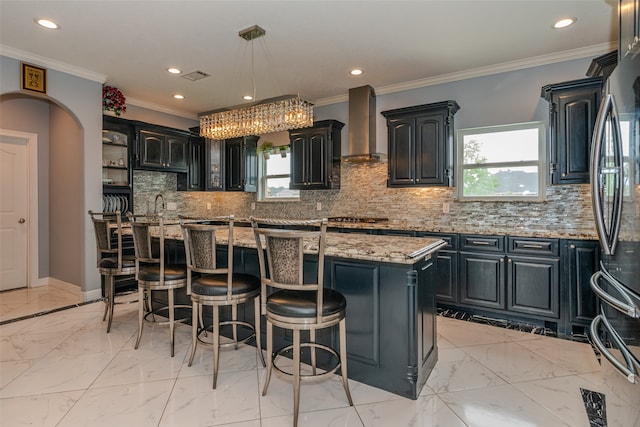 kitchen with wall chimney exhaust hood, a healthy amount of sunlight, a kitchen island, and tasteful backsplash