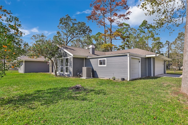 back of property with a lawn, central AC unit, and a garage