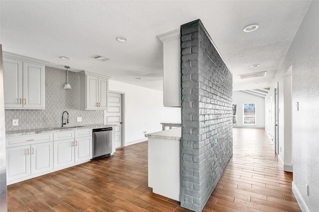 kitchen featuring light stone countertops, tasteful backsplash, stainless steel dishwasher, decorative light fixtures, and white cabinets