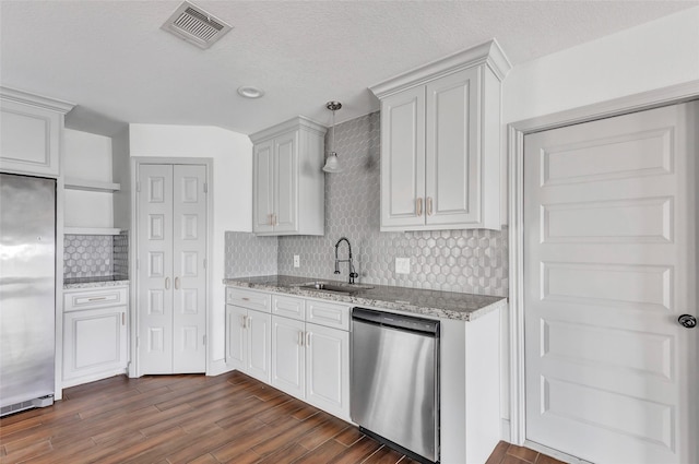 kitchen featuring white cabinets, sink, stainless steel appliances, and hanging light fixtures