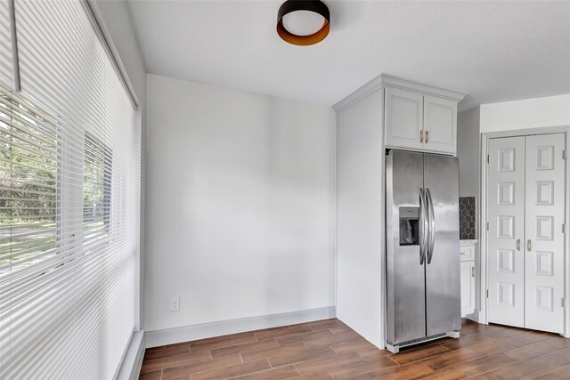 kitchen featuring stainless steel fridge, white cabinetry, and tasteful backsplash