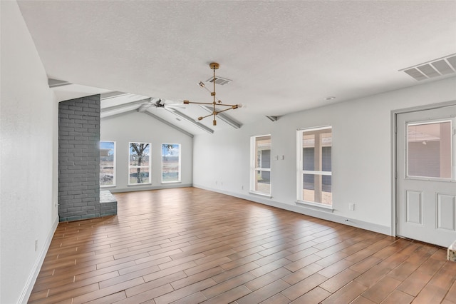 unfurnished living room with ceiling fan with notable chandelier, a textured ceiling, and lofted ceiling with beams