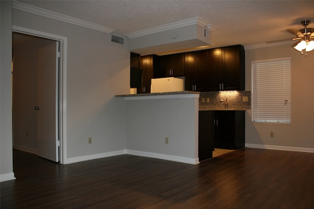 kitchen featuring kitchen peninsula, dark wood-type flooring, a textured ceiling, and crown molding