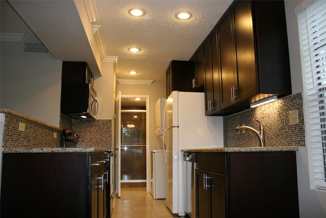 kitchen featuring light stone counters, crown molding, a textured ceiling, light tile patterned floors, and decorative backsplash