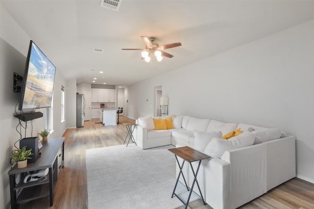 living room with light wood-type flooring and ceiling fan