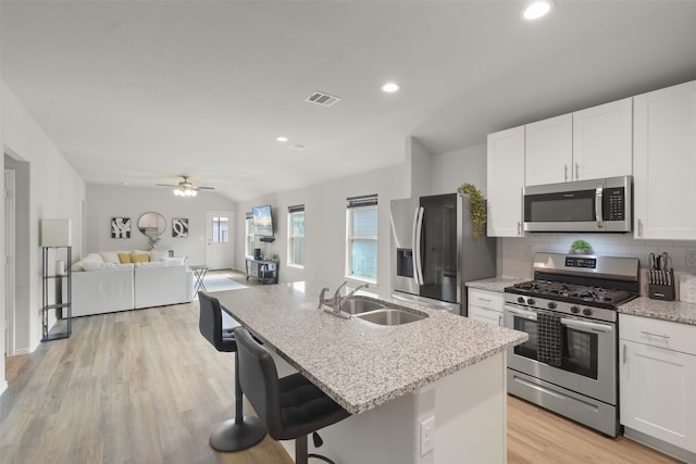 kitchen featuring stainless steel appliances, light wood-type flooring, white cabinetry, sink, and a kitchen island with sink