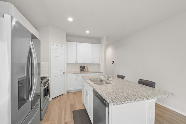 kitchen featuring white cabinetry, sink, appliances with stainless steel finishes, a kitchen island with sink, and light hardwood / wood-style flooring