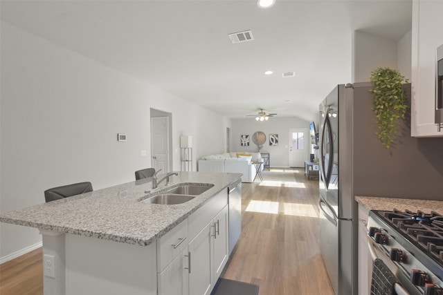 kitchen with ceiling fan, light hardwood / wood-style floors, a center island with sink, and white cabinets