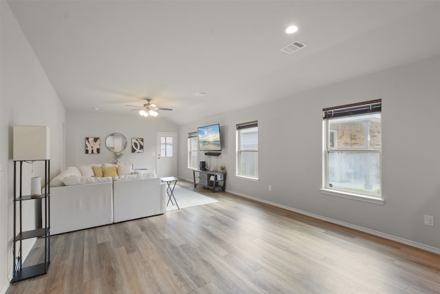 unfurnished living room featuring a wealth of natural light, light hardwood / wood-style floors, ceiling fan, and vaulted ceiling