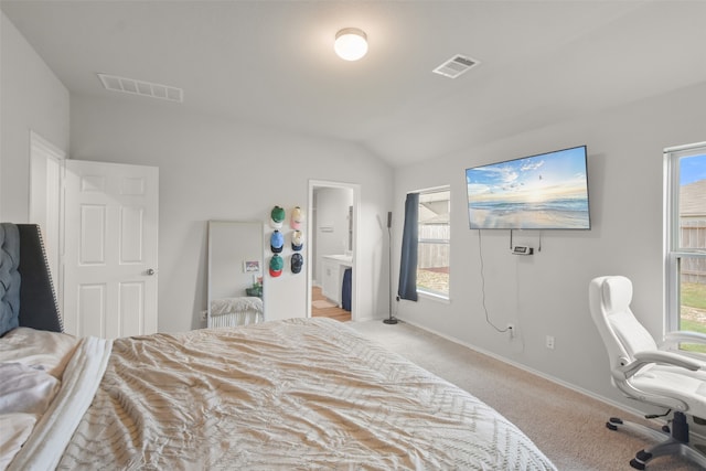 bedroom with ensuite bathroom, light colored carpet, and vaulted ceiling