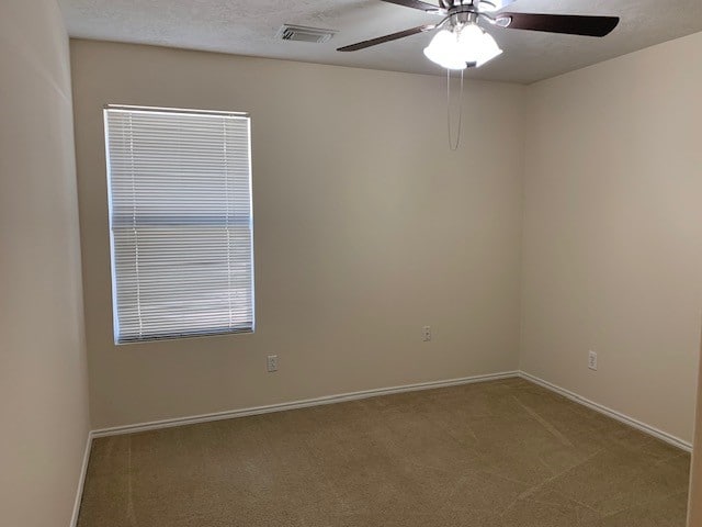 empty room featuring a textured ceiling, ceiling fan, and carpet floors