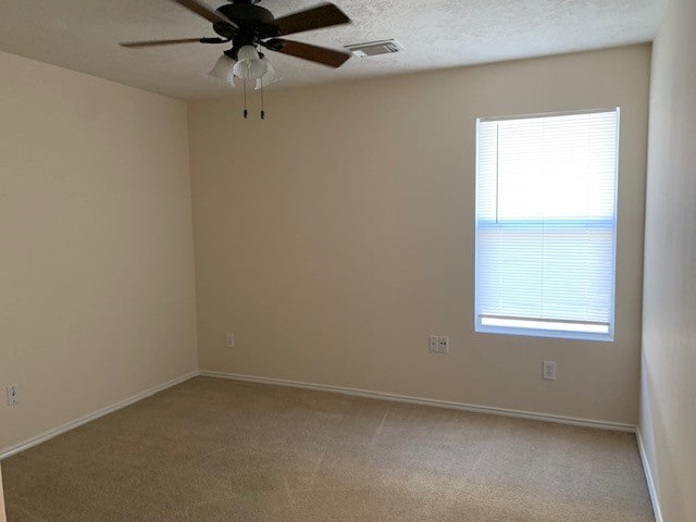 unfurnished room featuring a textured ceiling, light colored carpet, and ceiling fan