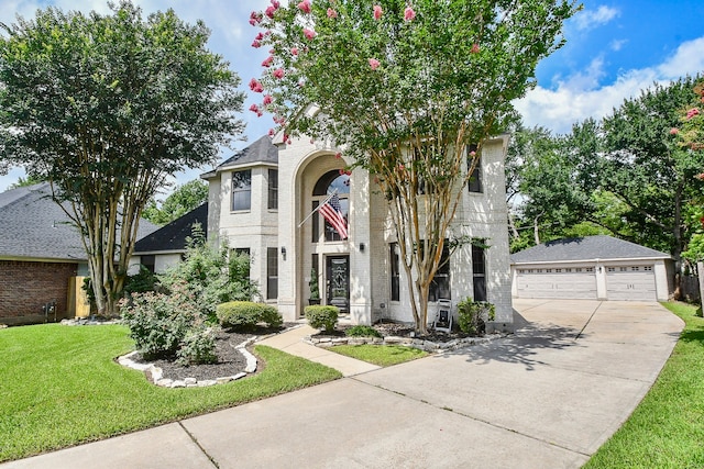 view of front of house featuring a garage, an outbuilding, and a front lawn