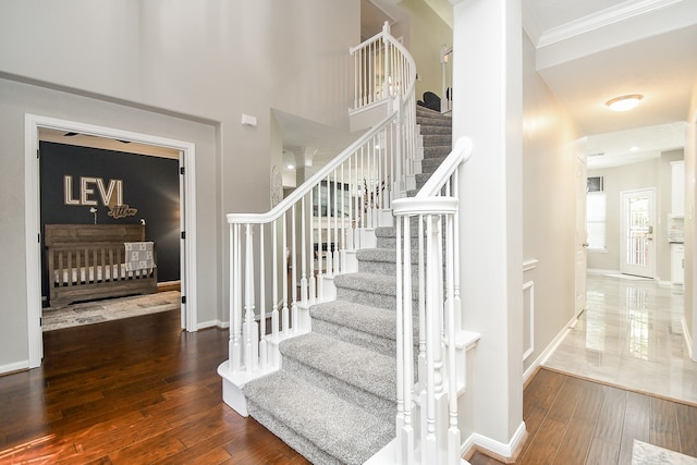 stairway with hardwood / wood-style flooring and crown molding