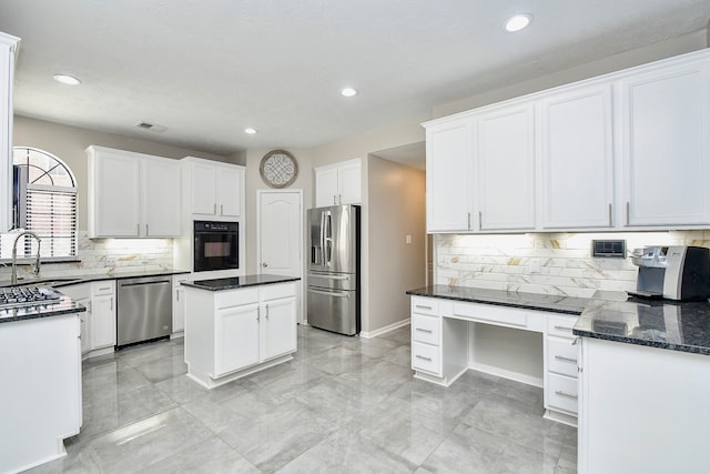 kitchen with decorative backsplash, stainless steel appliances, sink, white cabinetry, and a kitchen island