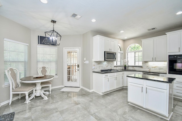 kitchen featuring appliances with stainless steel finishes, tasteful backsplash, white cabinetry, and pendant lighting