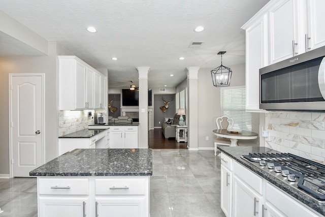 kitchen with gas cooktop, decorative backsplash, decorative columns, pendant lighting, and white cabinetry