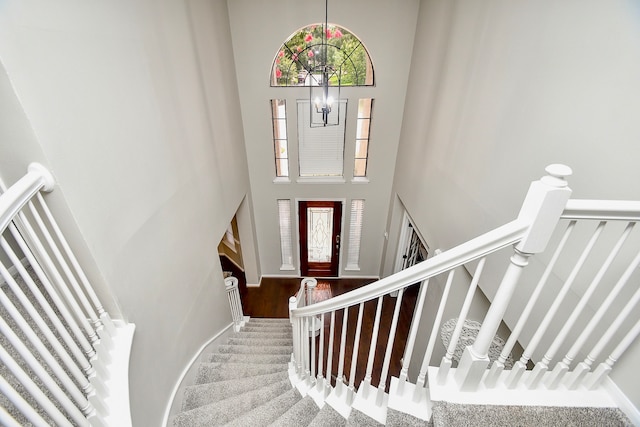 stairway with a high ceiling, a notable chandelier, and hardwood / wood-style floors