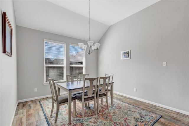 dining space featuring lofted ceiling, hardwood / wood-style flooring, and a notable chandelier