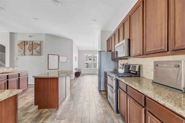 kitchen with light stone countertops, light hardwood / wood-style flooring, and appliances with stainless steel finishes