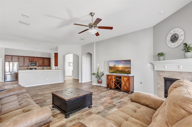 living room featuring a fireplace, light hardwood / wood-style floors, and ceiling fan