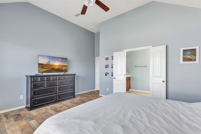 bedroom featuring high vaulted ceiling, light hardwood / wood-style floors, ceiling fan, and ensuite bath