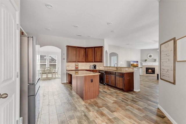 kitchen with kitchen peninsula, sink, a kitchen island, light wood-type flooring, and appliances with stainless steel finishes