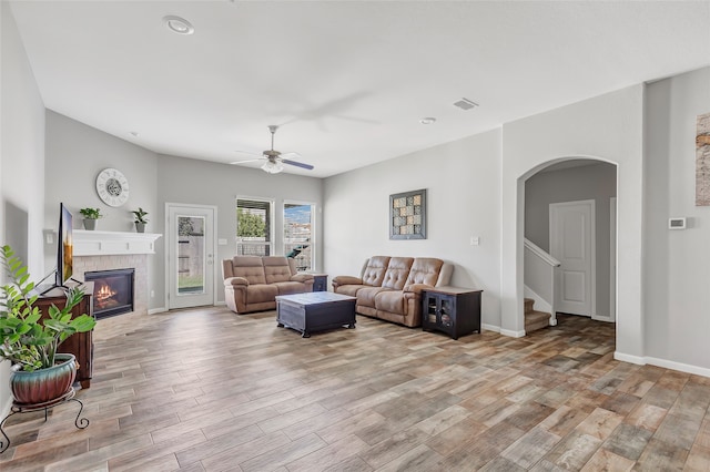 living room featuring a fireplace, ceiling fan, and light hardwood / wood-style flooring