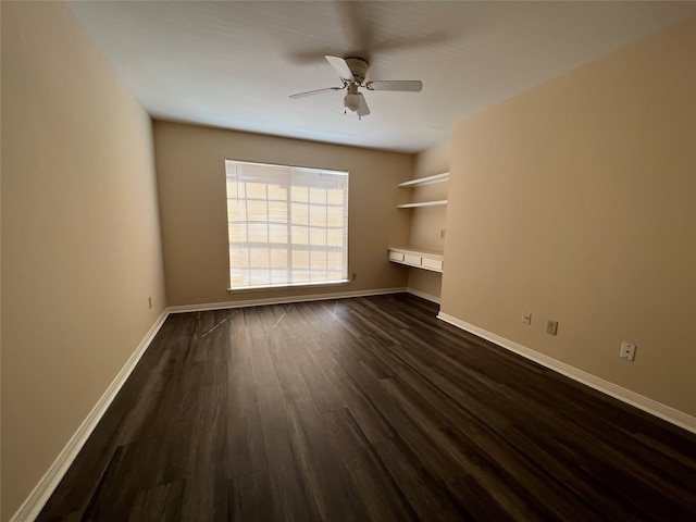 interior space with dark wood-type flooring, built in desk, and ceiling fan