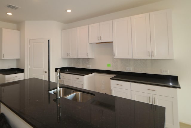 kitchen with backsplash, white cabinetry, and sink