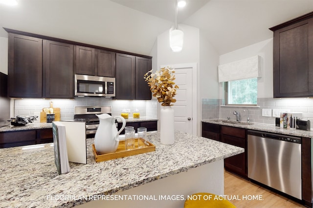 kitchen featuring hanging light fixtures, stainless steel appliances, vaulted ceiling, and sink