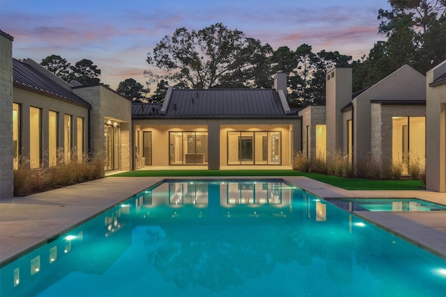 pool at dusk with a jacuzzi and a patio