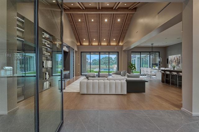 unfurnished living room featuring wood ceiling, hardwood / wood-style floors, a chandelier, high vaulted ceiling, and beamed ceiling