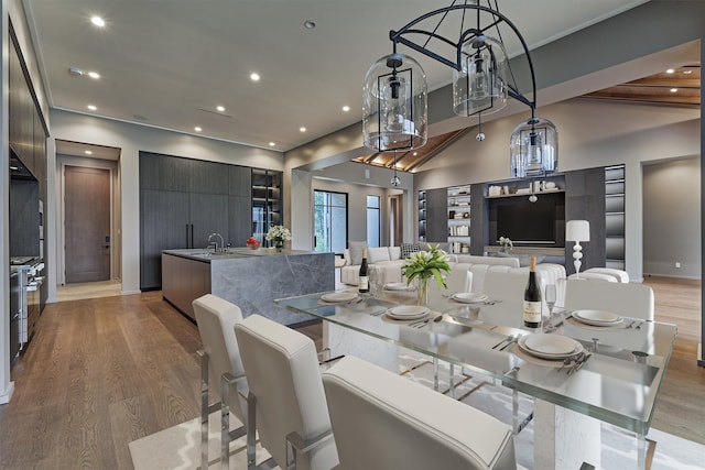 dining room with lofted ceiling with beams, light hardwood / wood-style flooring, and sink