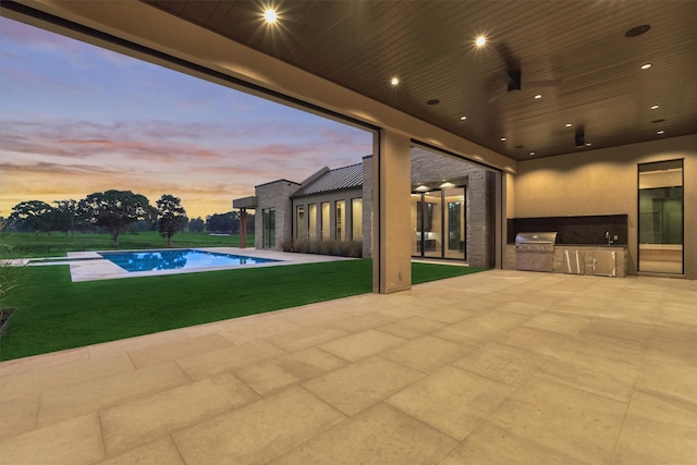 pool at dusk with a patio area, area for grilling, a lawn, and a grill