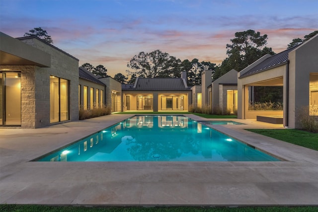 pool at dusk featuring a patio and a jacuzzi