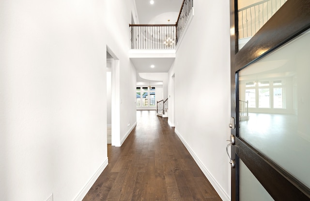 hall featuring dark hardwood / wood-style flooring, a healthy amount of sunlight, and a high ceiling