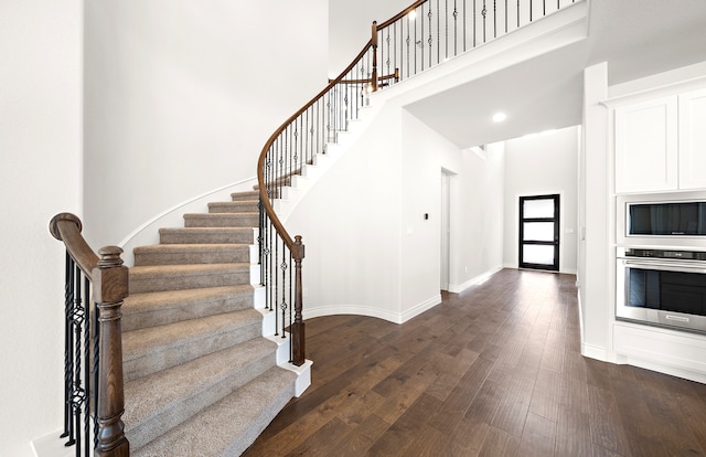 foyer entrance with dark wood-type flooring and a high ceiling