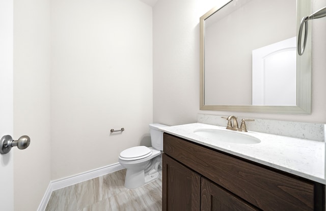 bathroom with toilet, vanity, and wood-type flooring