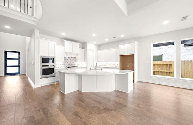 kitchen featuring white cabinetry, stainless steel appliances, and a center island with sink