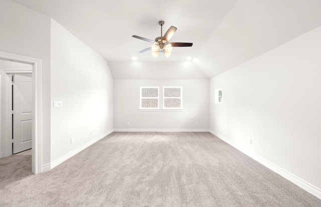 carpeted spare room with ceiling fan and vaulted ceiling