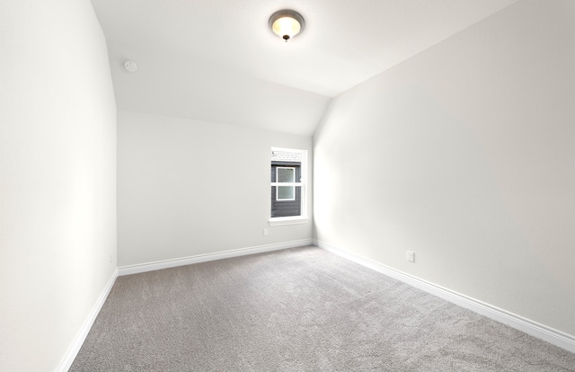 carpeted empty room with lofted ceiling