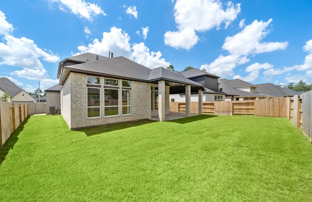 rear view of property with a lawn, central AC, and a patio area